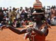 Traditional Ugandan dancer balances a clay pot on her head during a vibrant cultural celebration — experience Uganda with GoFurther 4x4 Car Rental.