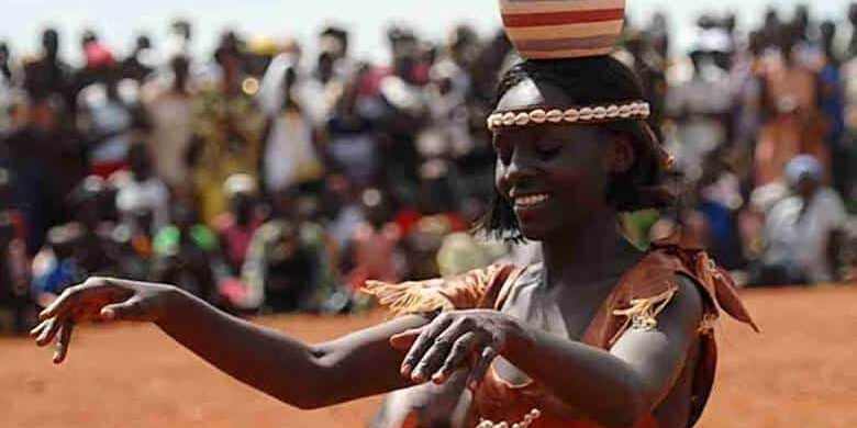 Traditional Ugandan dancer balances a clay pot on her head during a vibrant cultural celebration — experience Uganda with GoFurther 4x4 Car Rental.