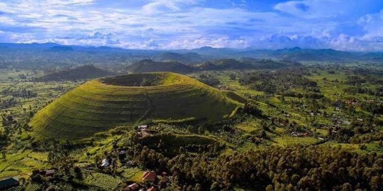 Aerial view of a lush volcanic crater surrounded by green farmlands in Uganda.